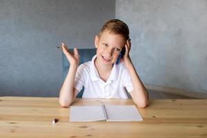 Cute boy writes in an open notebook and looks at the phone. Talking on the phone photo