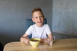 Cute boy eats a dry breakfast at home and smiles photo