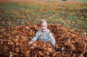 A happy boy stands in the autumn forest photo