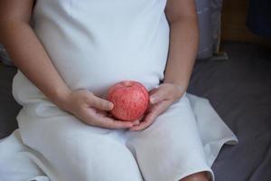 Young Asian Pregnant Woman using rattle toy to play with her unborn baby photo