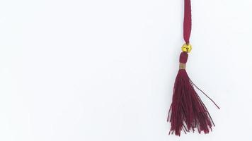 Close up view of red bookmark strap used for Al Quran. Red silk tassels isolated on white background for creating graphic concepts. photo