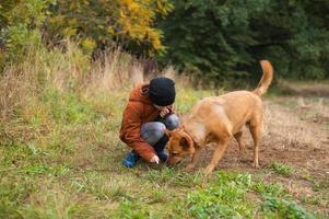 un chico es sentado fuera de con un grande perro foto