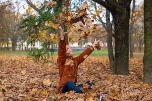 The boy throws autumn yellow leaves that fly at him photo