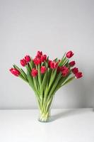 Red kung fu tulips stand in a glass vase on the table. Bouquet of flowers photo