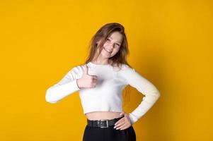 Young caucasian cheerful woman showing thumbs up on bright yellow background photo