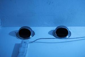 Exhaust holes on white walls under blue light photo