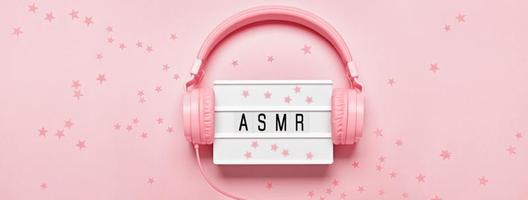Headphones, ASMR letters lightbox and confetti on pink banner. ASMR Stress-relieving sounds concept, flat lay, monochrome colors photo