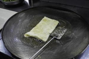 Frying Martabak Telor or omelet martabak in hot oil. Savoury pan-fried pastry stuffed with egg, meat, and spices. Traditional food snacks from Indonesia. photo