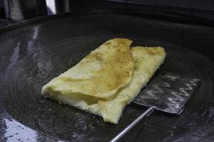 Frying Martabak Telor or omelet martabak in hot oil. Savoury pan-fried pastry stuffed with egg, meat, and spices. Traditional food snacks from Indonesia. photo