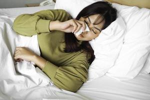 A sad young Asian woman is crying while lying on the bed photo