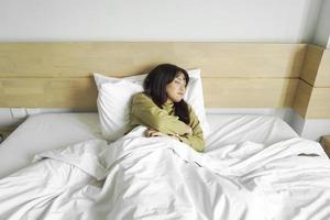 Young beautiful Asian woman sleeping in her bed and relaxing in the morning photo