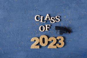 Class of 2023 banner concept. Wooden number 2023 with graduated cap on podium on dark background photo