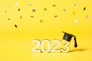 Class of 2023 concept. Wooden number 2023 with graduated cap on colored background photo