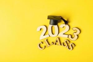 Class of 2023 concept. Wooden number 2023 with graduated cap on colored background photo