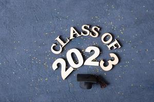 Class of 2023 banner concept. Wooden number 2023 with graduated cap on podium on dark background photo