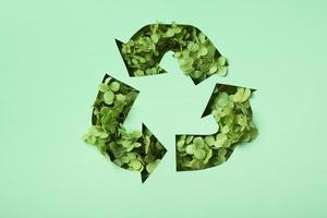 Green flowers under paper cut recycling symbol. Save planet recycling cloth concept photo