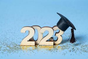 Class of 2023 concept. Wooden number 2023 with graduated cap on colored background photo