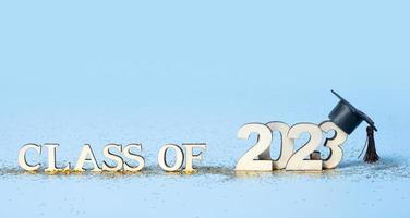 Class of 2023 concept. Wooden number 2023 with graduated cap on colored background photo