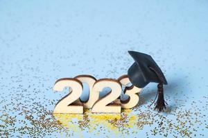 Class of 2023 concept. Wooden number 2023 with graduated cap on colored background photo