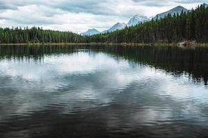 Herbert lake in Alberta, Canada on a cloudy day with stunning mountains and water reflections photo