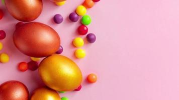 Golden Easter eggs and candies on pink background. Happy spring holiday. video
