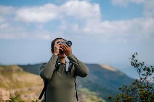 joven trekking hembra utilizar cámara fotografía en rocoso montaña pico foto