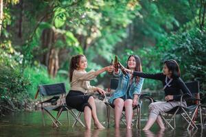 Young women sitting and drink beverage  while camping in forest photo