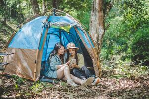 Asian pretty woman and friend use smartphone selfie on camping photo