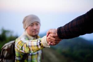 Close-up of Two male hikers helping each other climb up a mountain photo