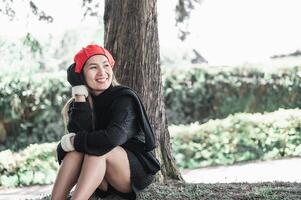 Portrait of Happy Asian young woman sitting on a lawn under a tree in park photo