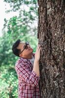 Portrait of Happy Asian man hugging a tree in forest photo