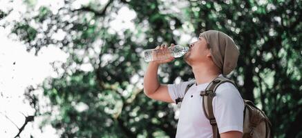 Portrait Asian traveler man with backpack drinking water photo