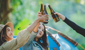 Young woman cheer and drink beverage front of camping tent photo