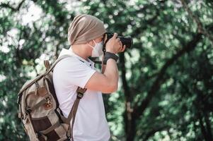 hombre viajero asiático con mochila tomando una foto en el parque