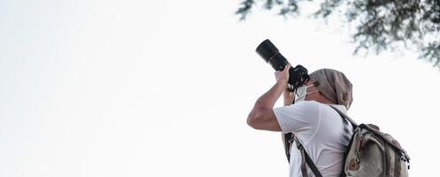 Asian traveler man with backpack taking a photo in the park