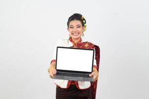retrato de hermosa tailandés mujer en tradicional ropa posando con ordenador portátil computadora foto
