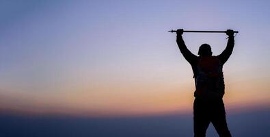 Silhouette of cheering hiking man open arms to the sunrise stand on mountain photo