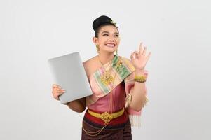 Young beautiful woman in northeastern dress holding laptop posting photo