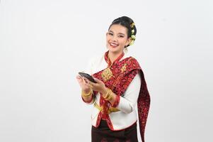 Young beautiful woman dress up in Thai northern region pose with smartphone photo