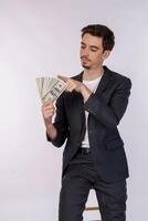 retrato de un hombre alegre señalando con el dedo un montón de billetes de dinero sobre fondo blanco foto