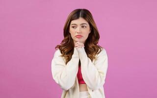 retrato de mujer joven rezando con la mano doblada o pidiendo un deseo aislado sobre fondo rosa foto