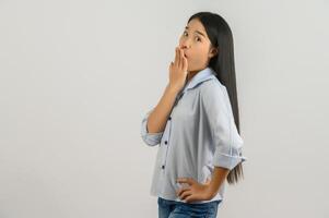 Portrait of Young surprised asian woman in blue shirt puts her hand over her mouth isolated on white background photo