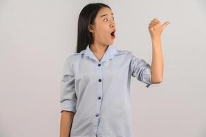 Portrait of young asian woman pointing with two hands and fingers to the side over isolated white background photo