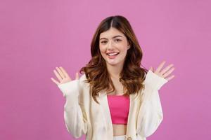 Portrait of Excited surprised young woman celebrating victory with happy smile and winner expression with raised hands isolated over pink background photo