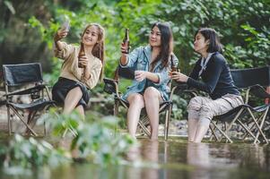 Group of women drink beer and soaked feet in stream photo