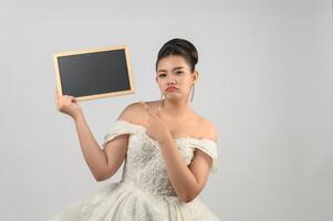 Young asian beautiful bride pose with blank blackboard in hand photo