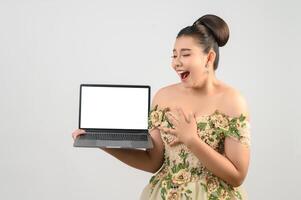 Young asian beautiful bride pose with mock up laptop computer in hand photo