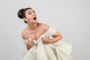 Una joven novia asiática hermosa posa con una sensación emocionada de fondo blanco foto