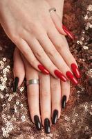 Hands of a young girl with red  and black manicure on nails photo