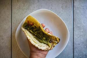 Traditional mexican tortilla with nopales opuntia in hand on the table photo